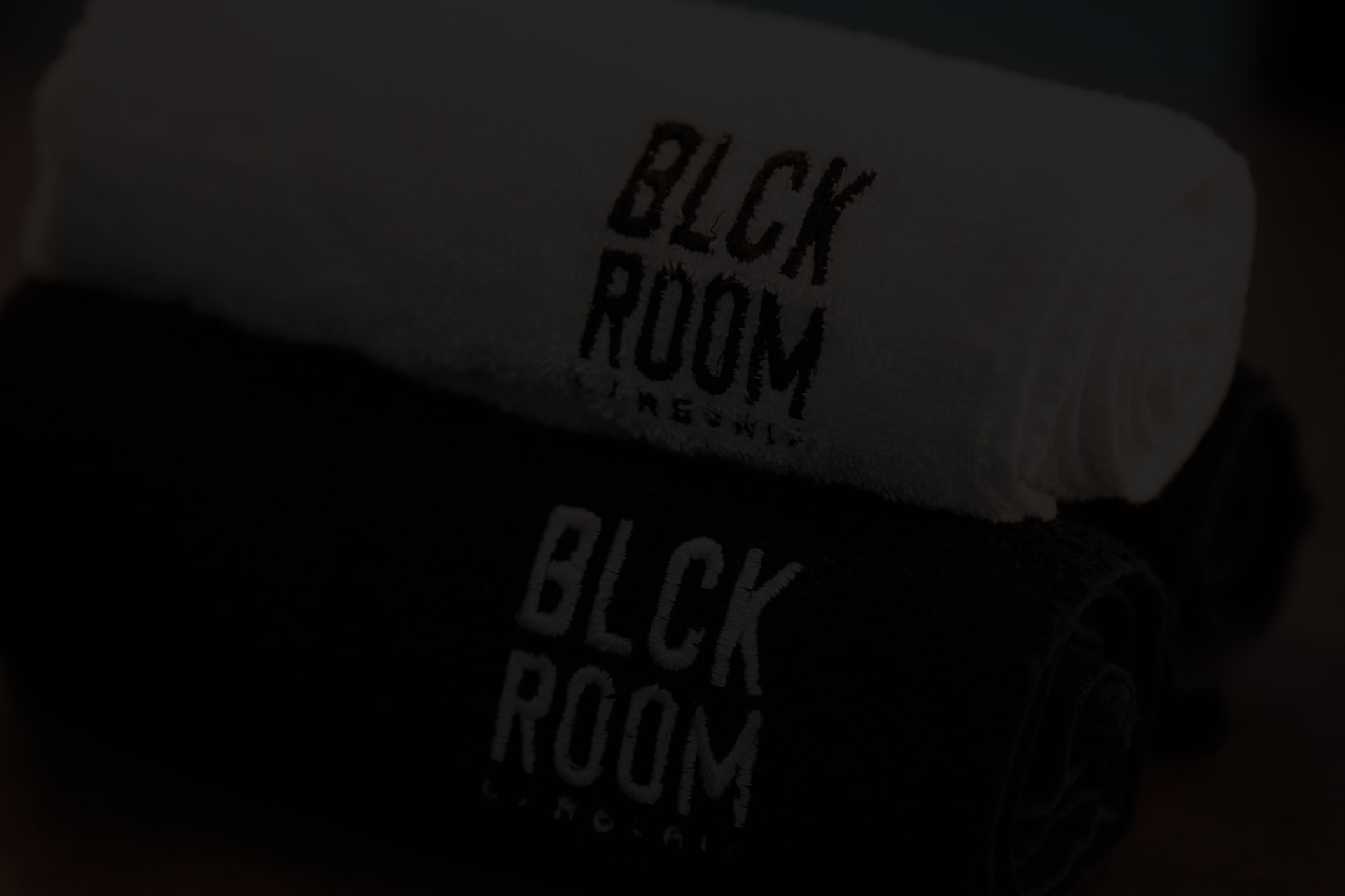 Asciugamani con logo BLCK ROOM piegati nella stanza nera